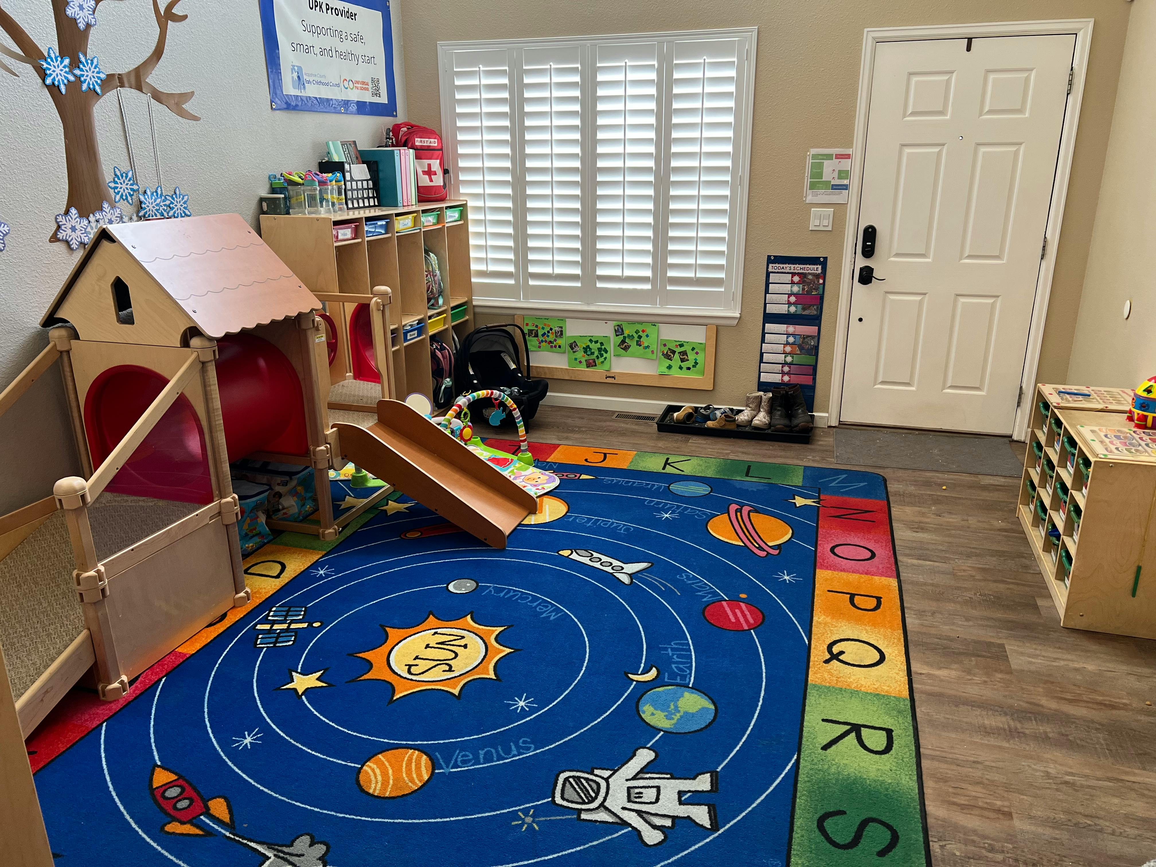 Playroom with a solar system rug, wooden playhouse, and slide