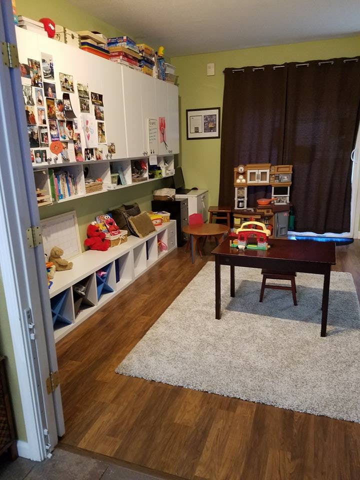 Playroom with storage shelves, small tables, and a rug