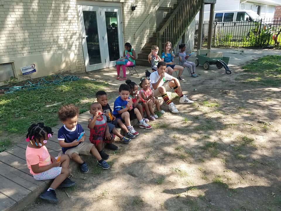Group of children and adults sitting outdoors