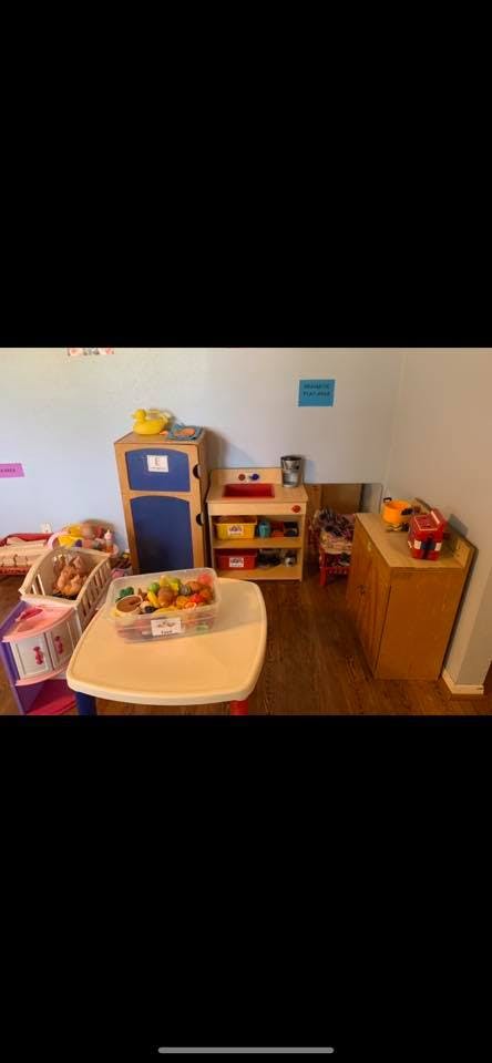 Playroom with toy kitchen, table with toy food, and crib