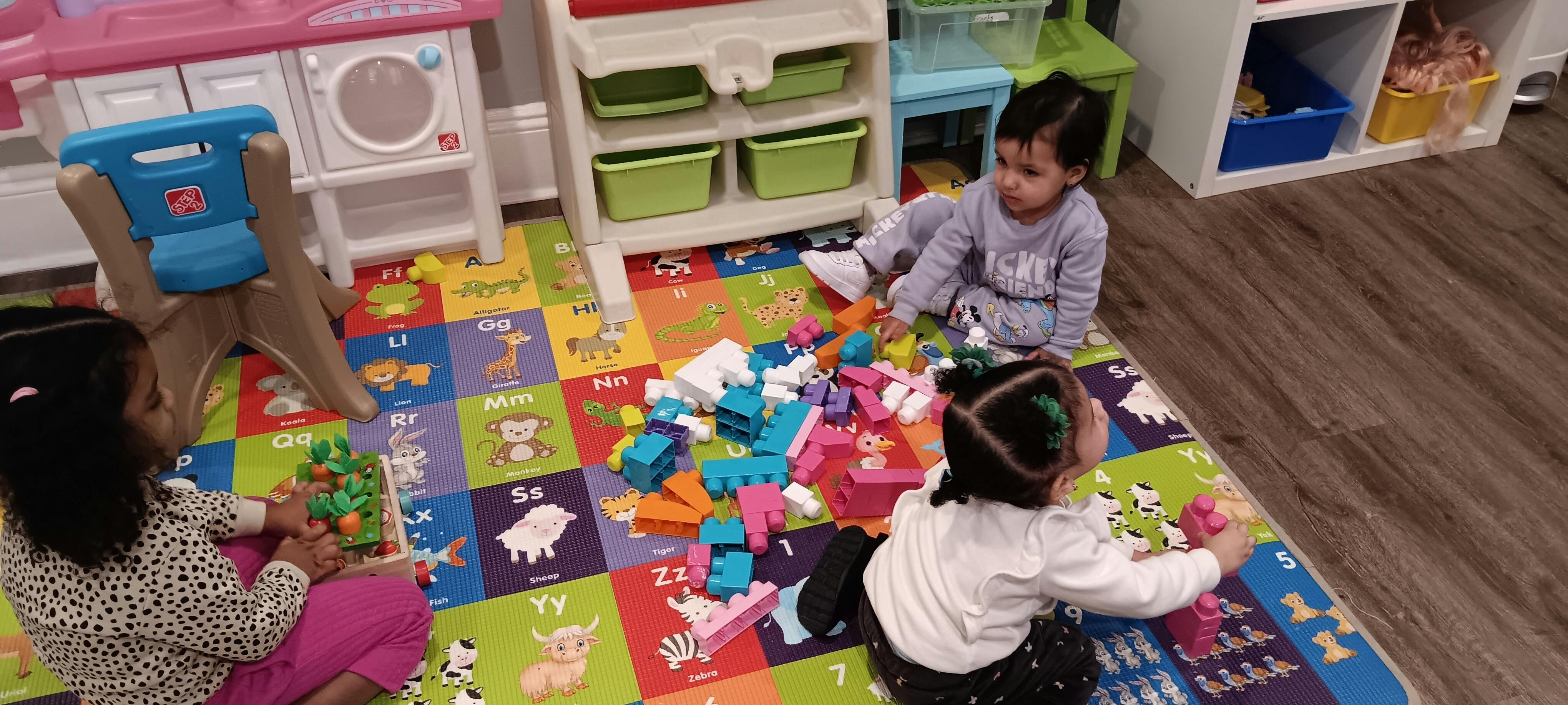 Three children playing with toys on a colorful mat