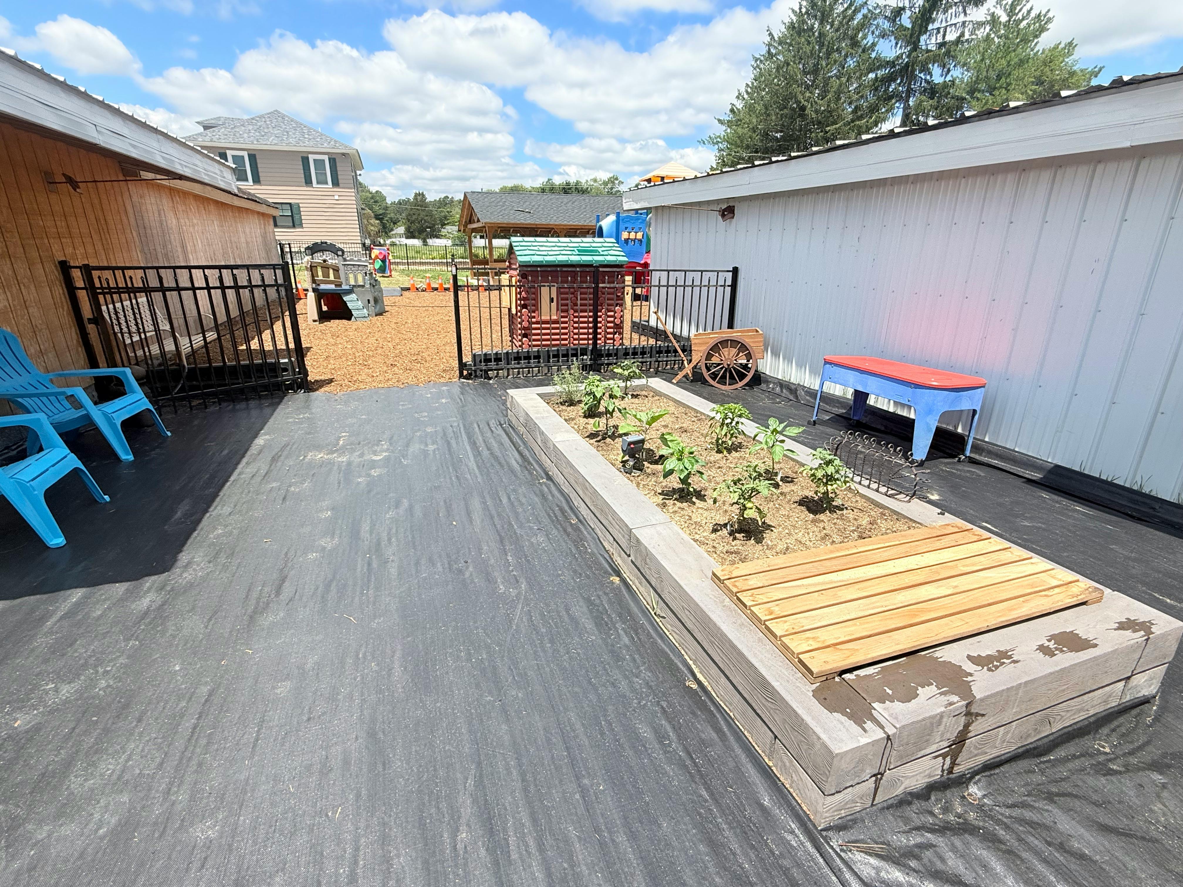 Raised garden bed in a backyard with playground equipment in the background