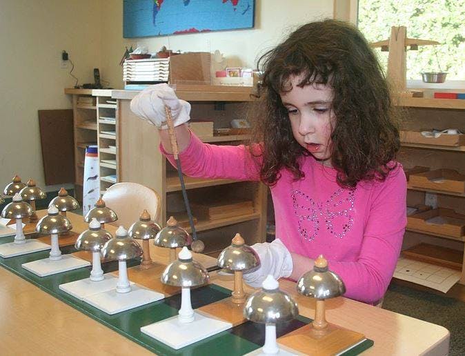 Child playing with a set of bells in a classroom