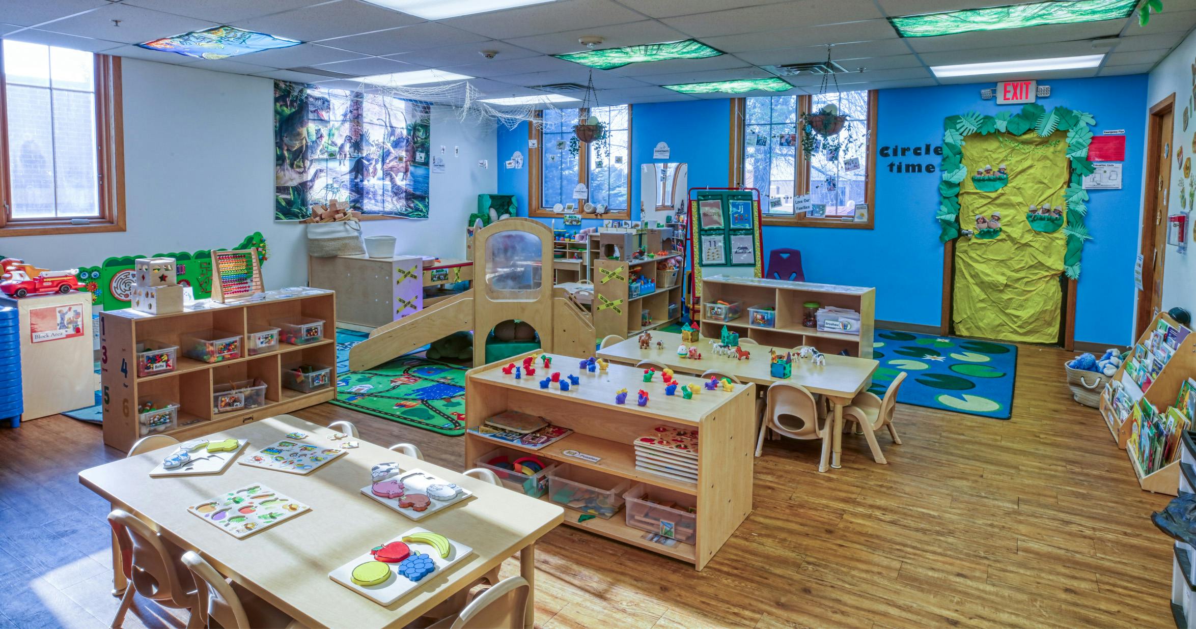 An empty early childhood classroom with multiple activity tables and play areas