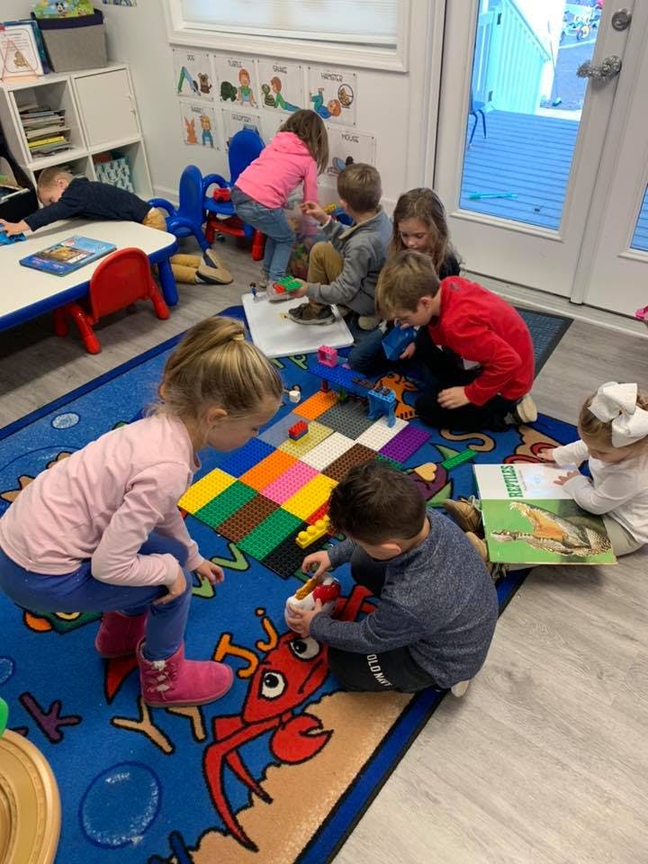 Children playing with toys and reading books on a colorful rug