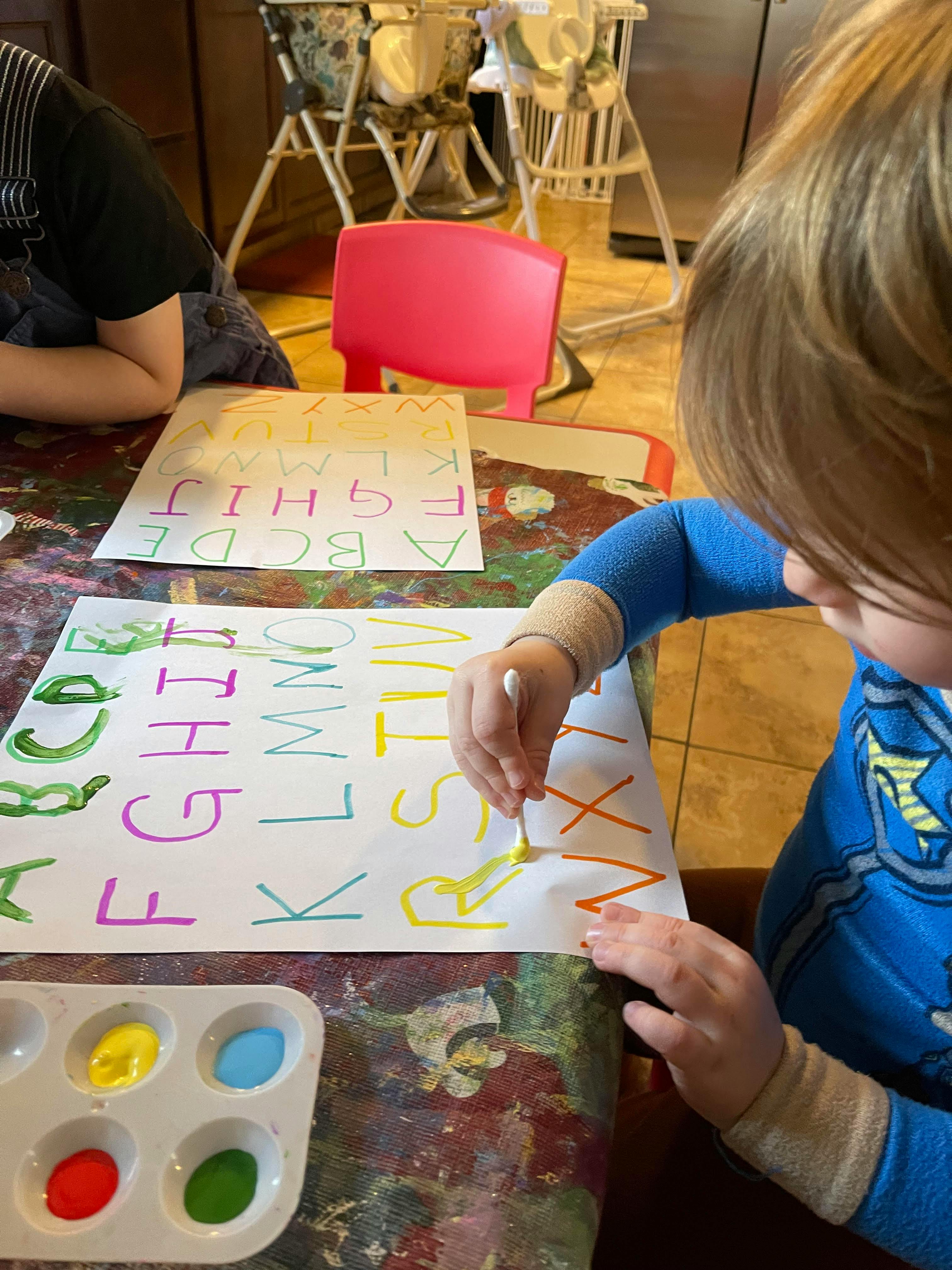Child painting letters on a sheet of paper