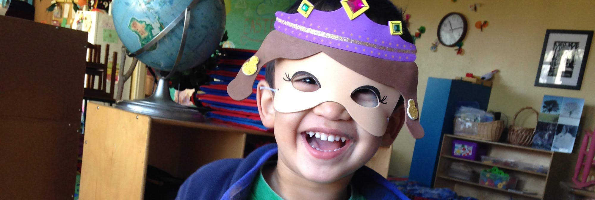 Child wearing a paper mask and crown