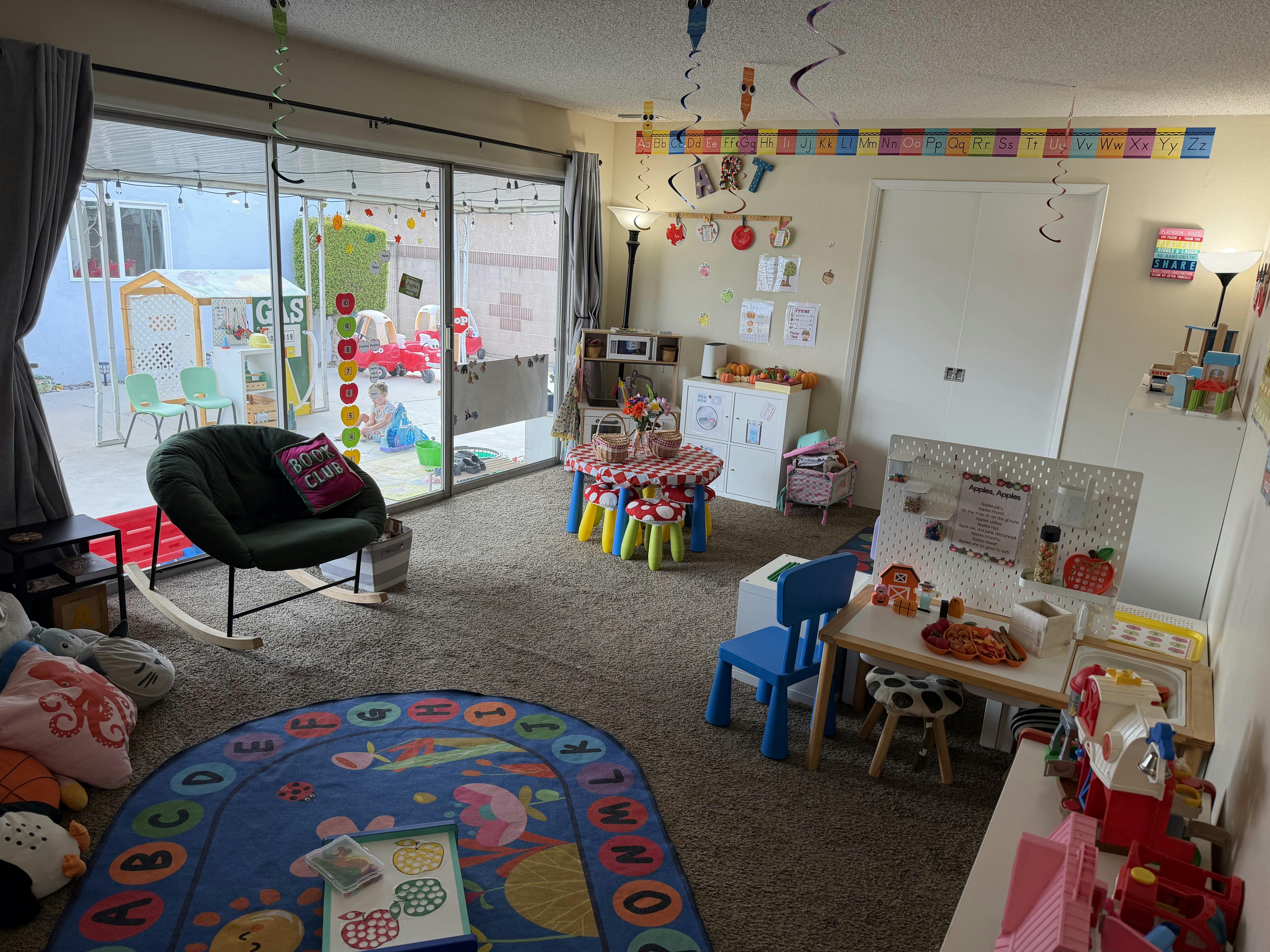 Colorful playroom for children with toys, activity tables, and alphabet rug