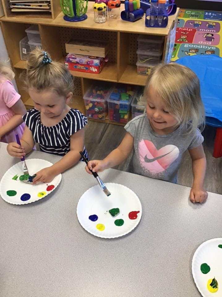 Two children painting with brushes and paint on paper plates