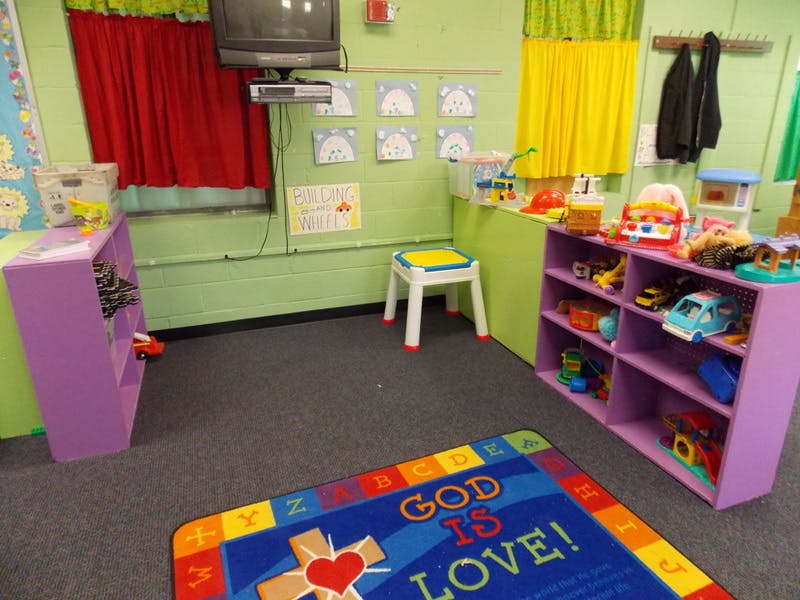 Playroom with toys on shelves and a rug with "God is Love" text