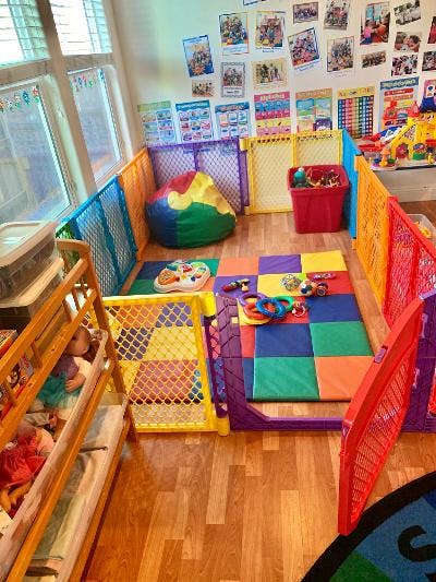 Play area with colorful fences, beanbag, and foam mats with toys