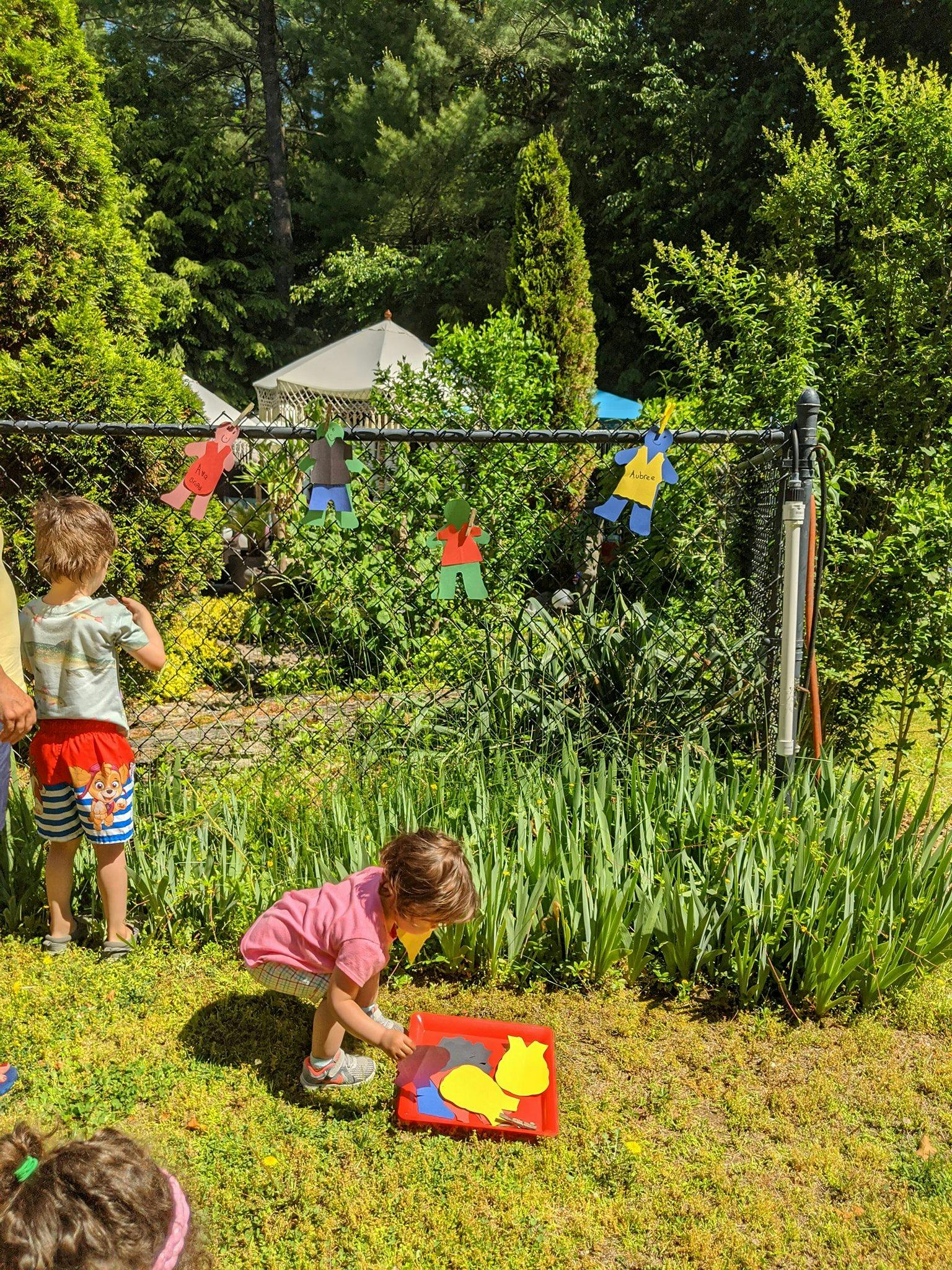 Child playing with shapes on a red tray outdoors