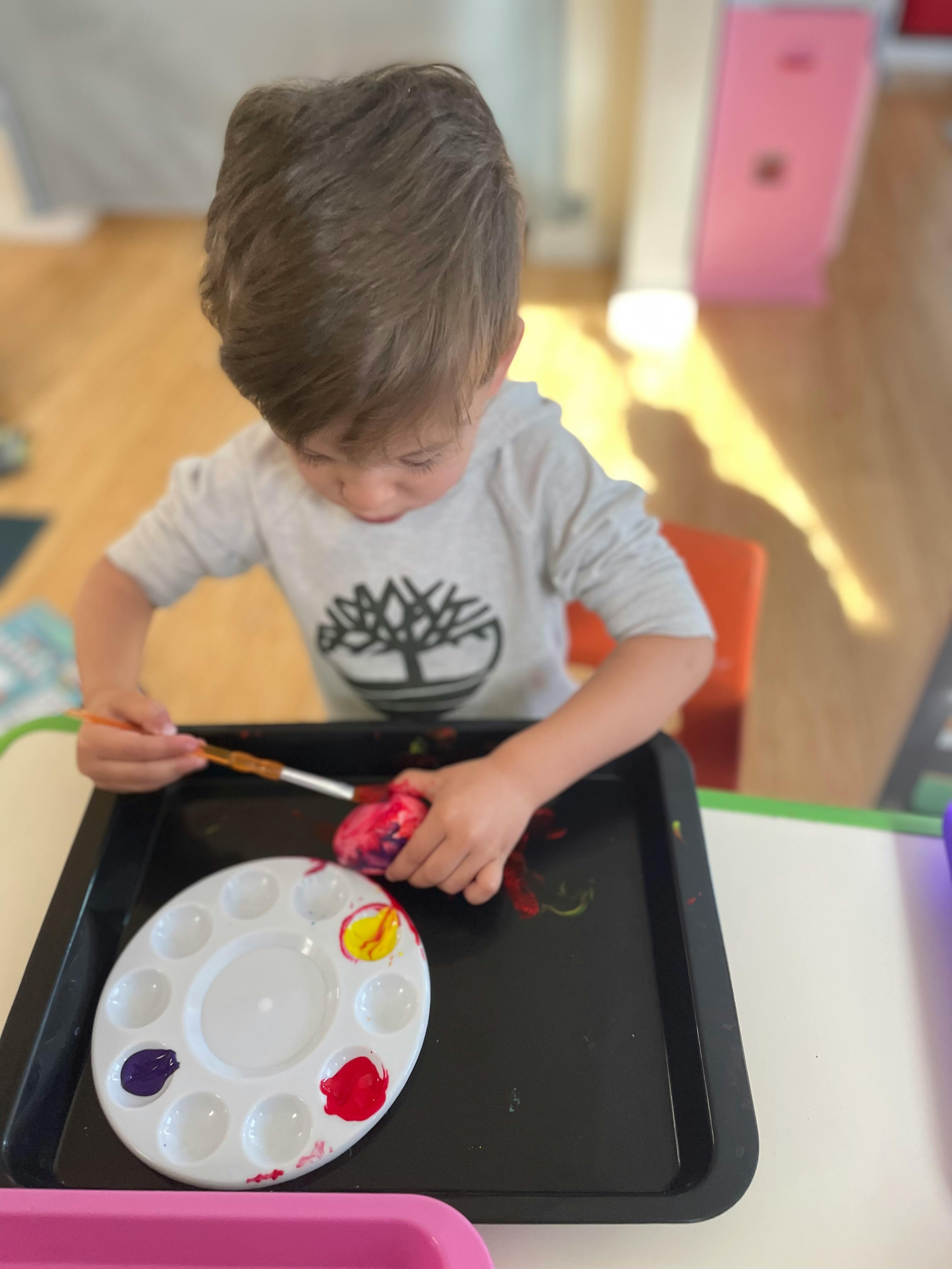 Child painting an object with a brush and paint palette