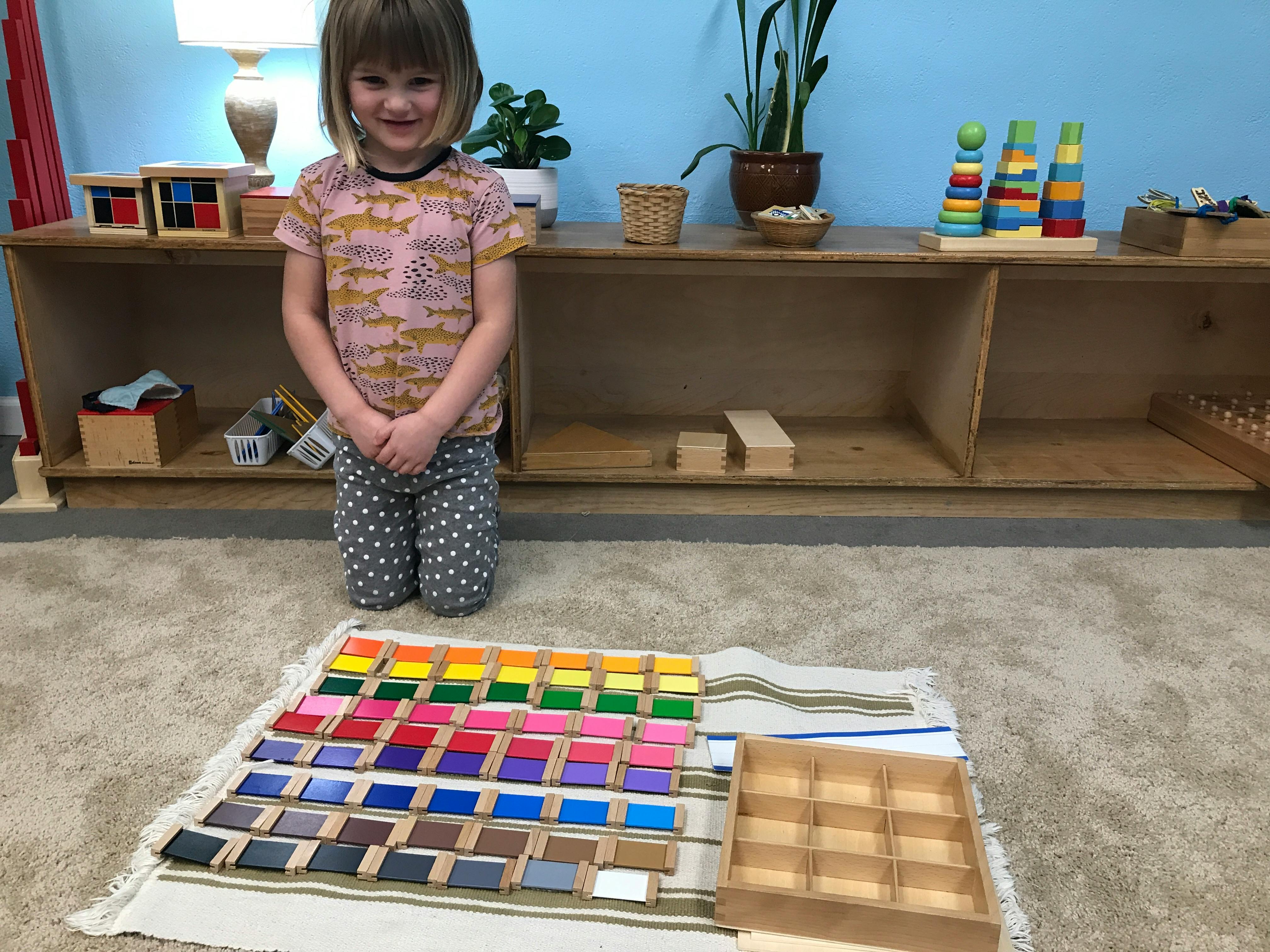 Child kneeling in front of colorful blocks arranged on a mat