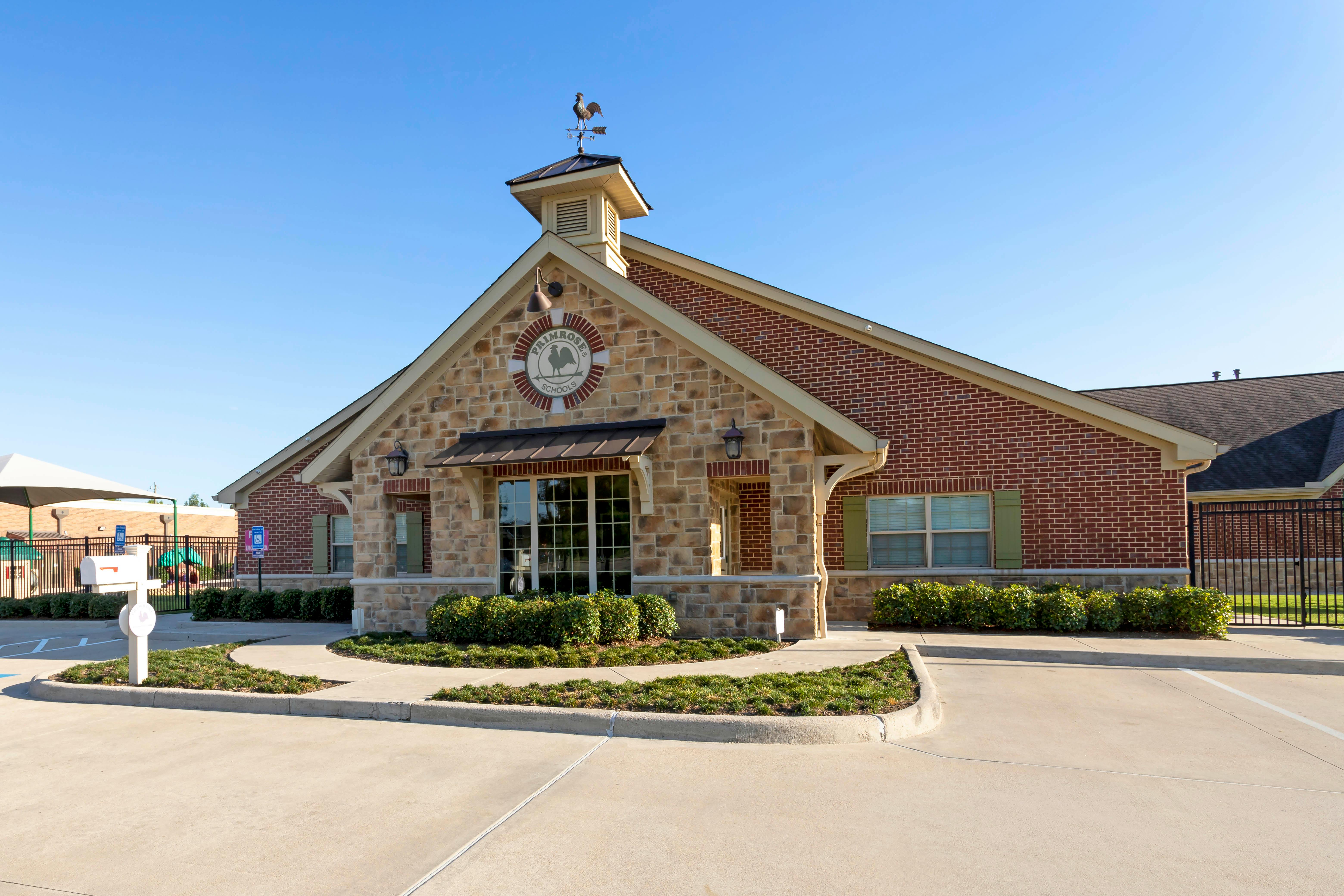 A brick building with a stone facade and a sign that says Primrose Schools