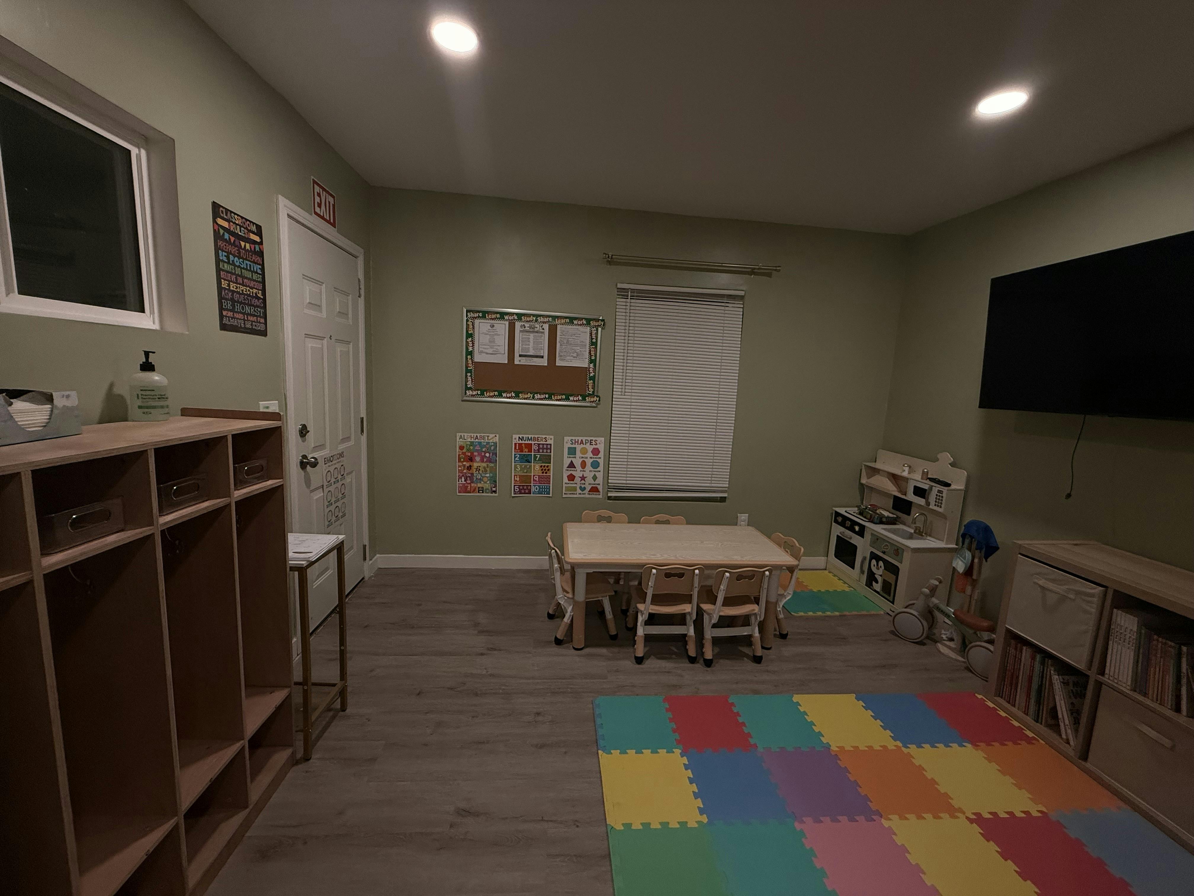 Playroom with a small table, chairs, toy kitchen, and colorful floor mats