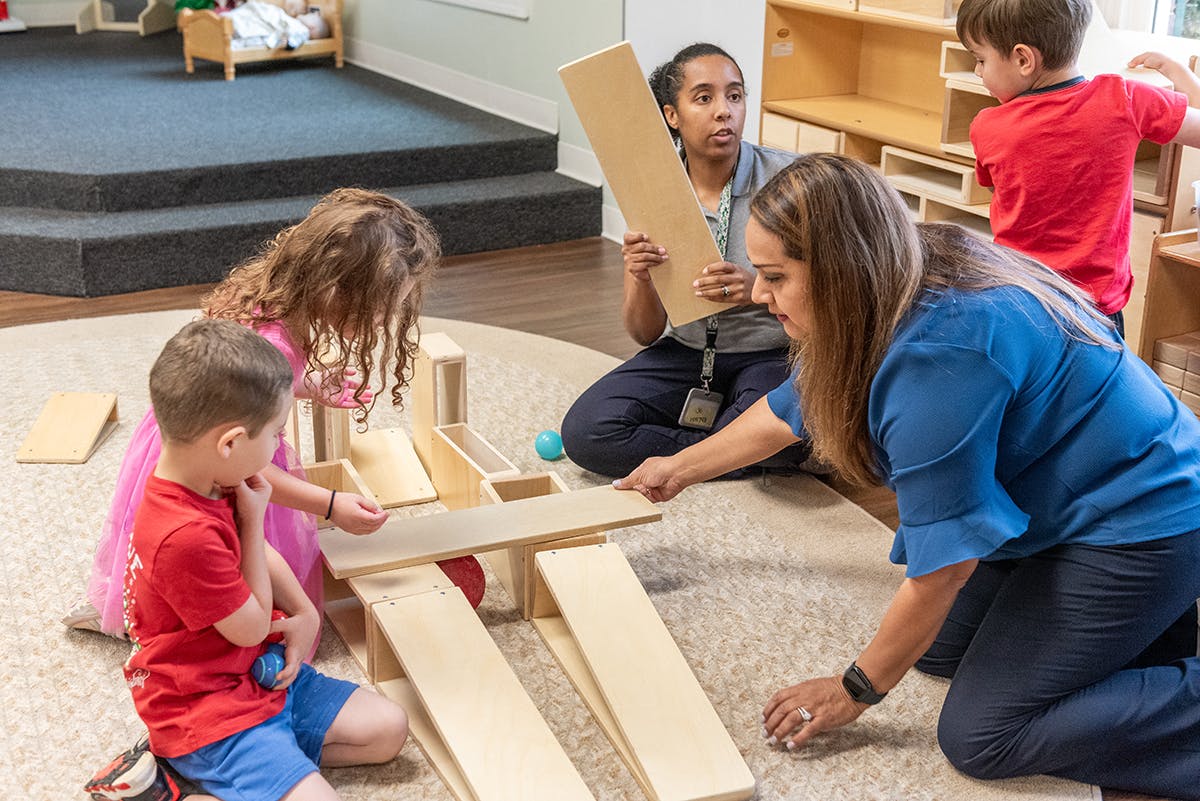Adults and children building with wooden blocks and ramps
