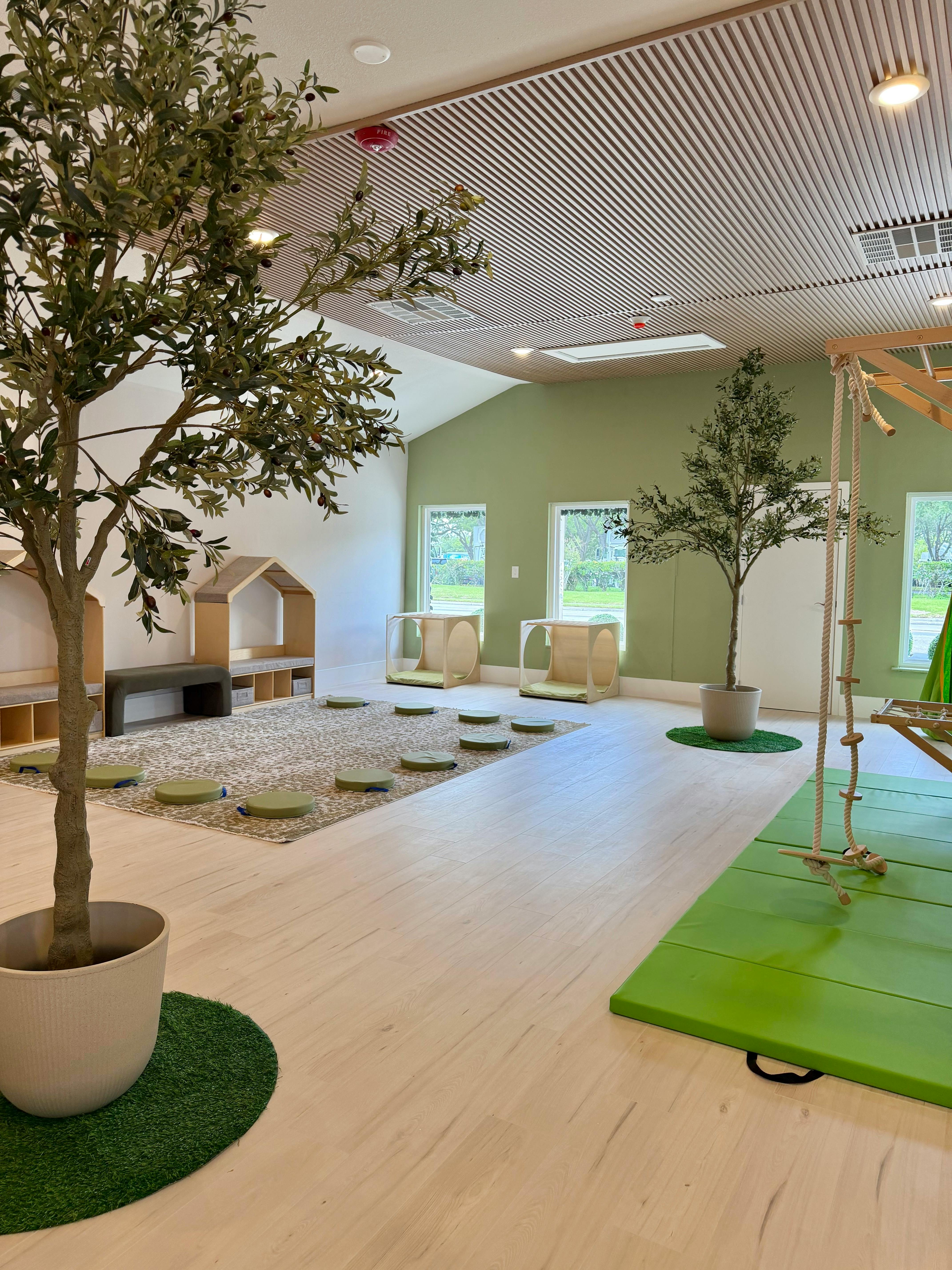 Interior of an activity room with wooden play structures and floor cushions