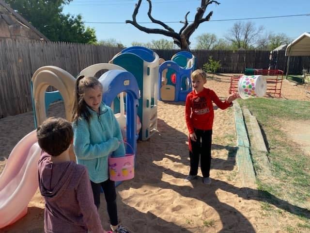 Three children on a playground with sand and play structures