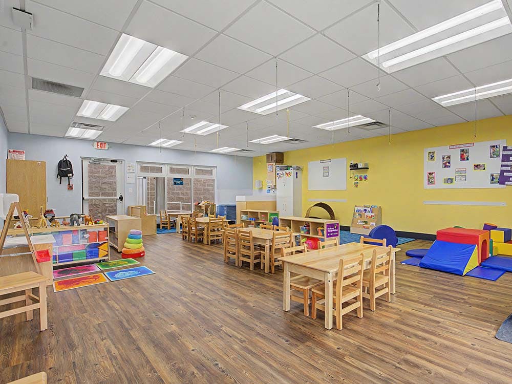 Classroom with wooden tables and chairs, and play equipment