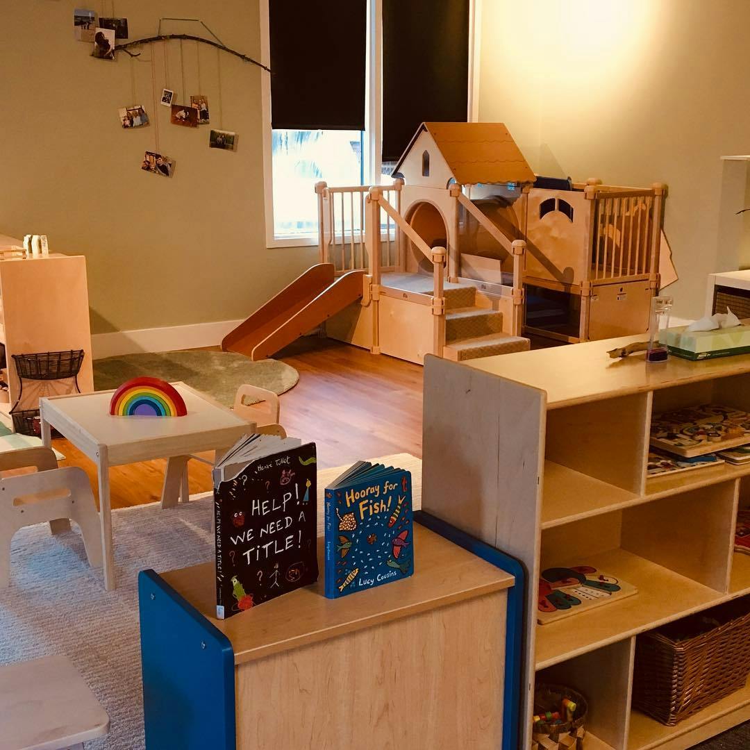 Indoor play area with wooden play structure, slide, and books