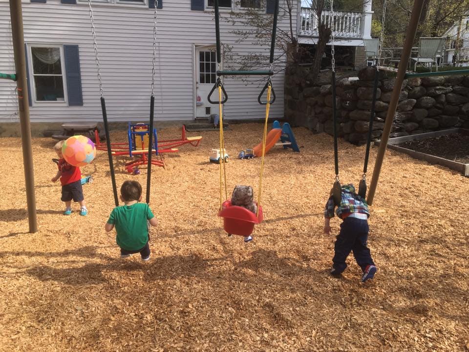 Children playing on swings and with a ball on a playground