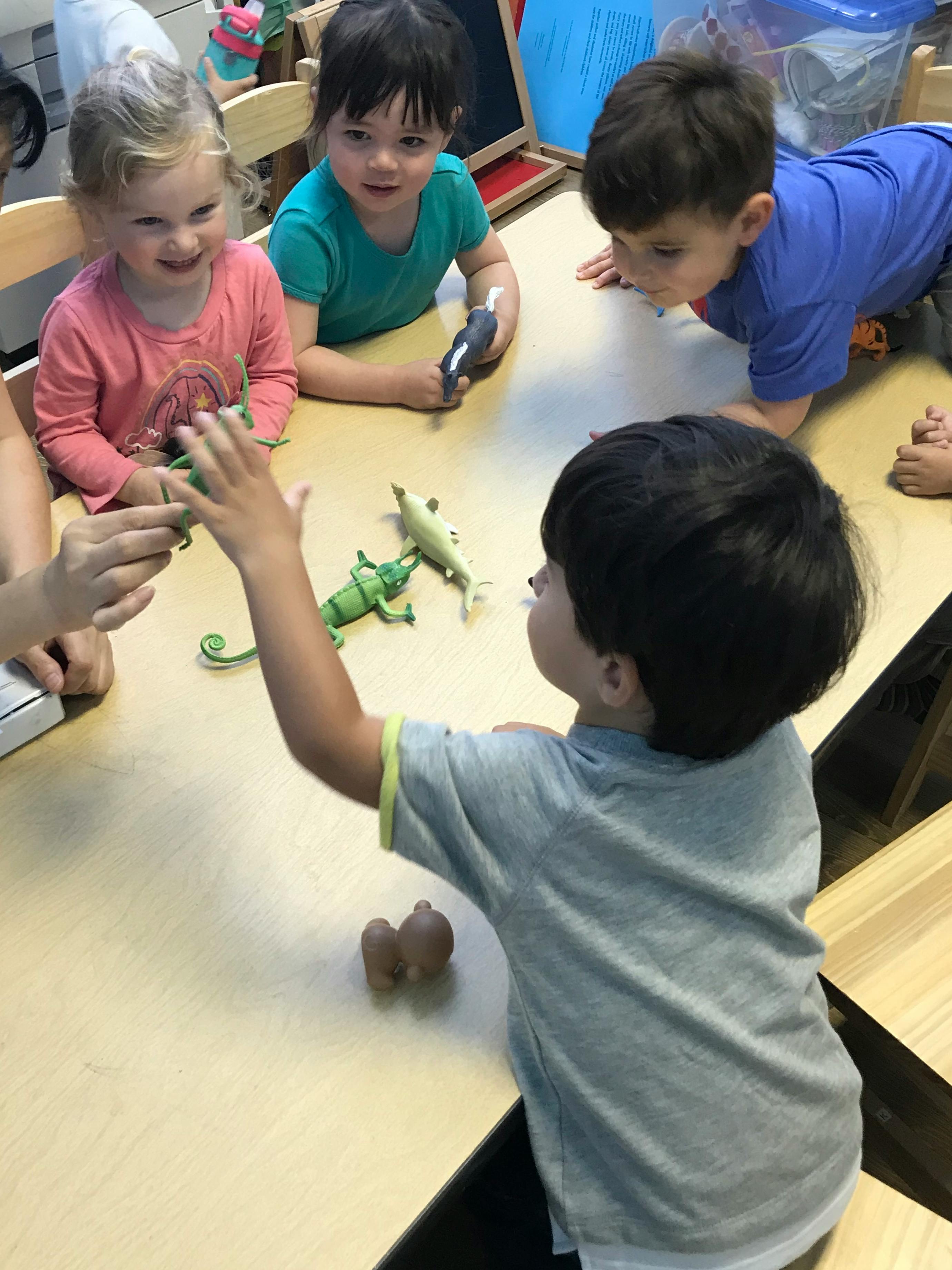 Children playing with toy animals on a table