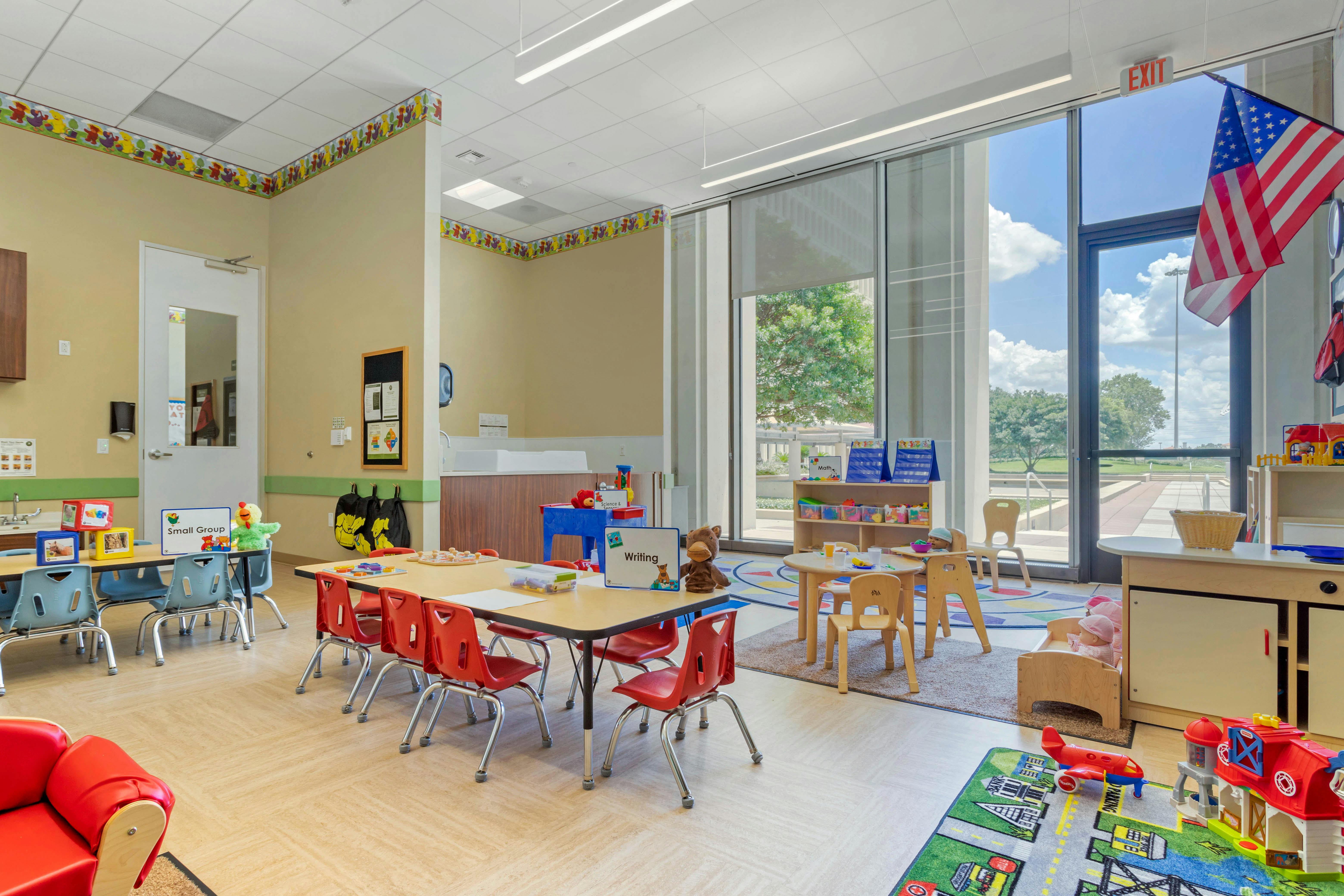 An empty early childhood classroom with multiple tables and chairs