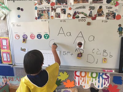 Child writing on a whiteboard in a classroom