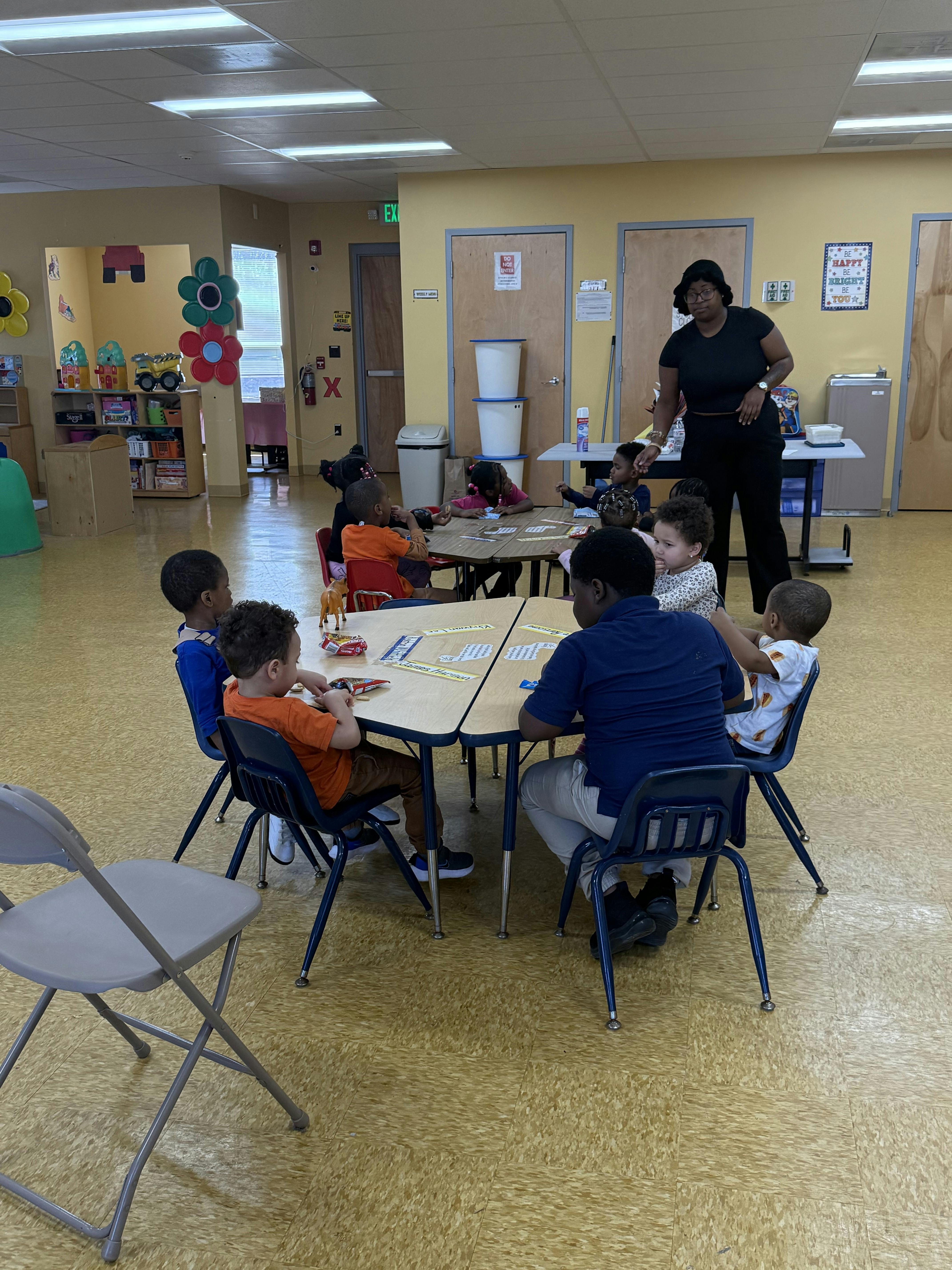 Adult supervising children seated at tables in a classroom