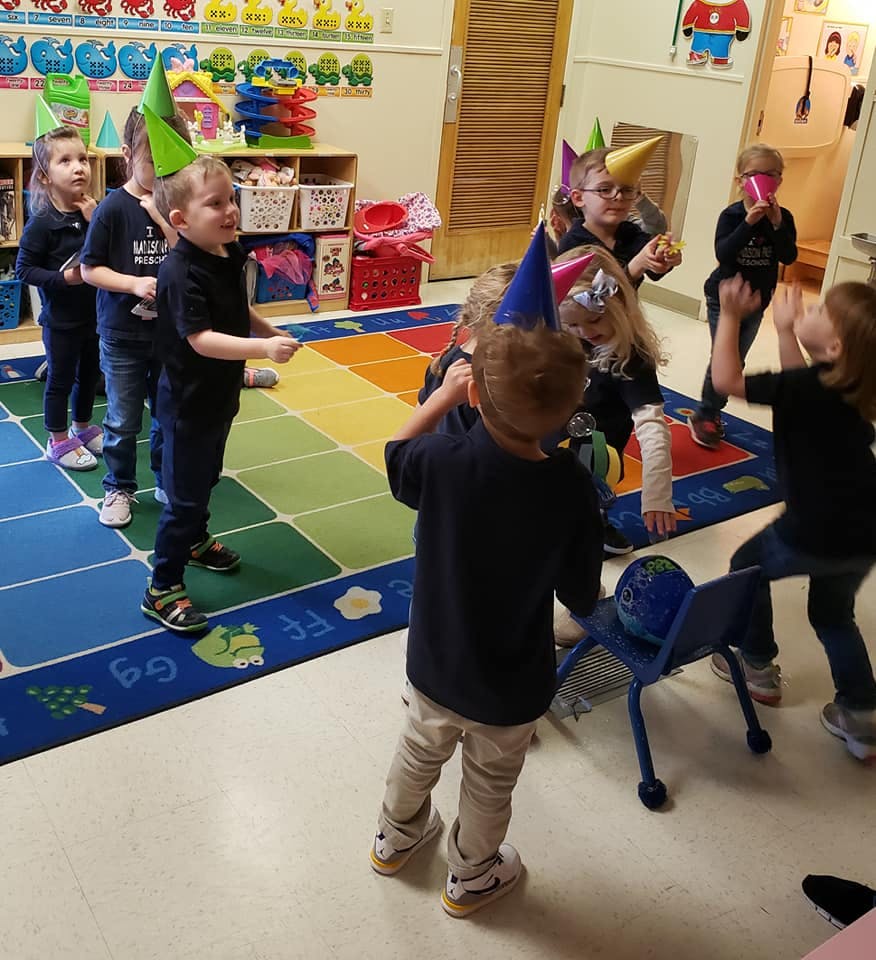 Children in party hats playing in a classroom