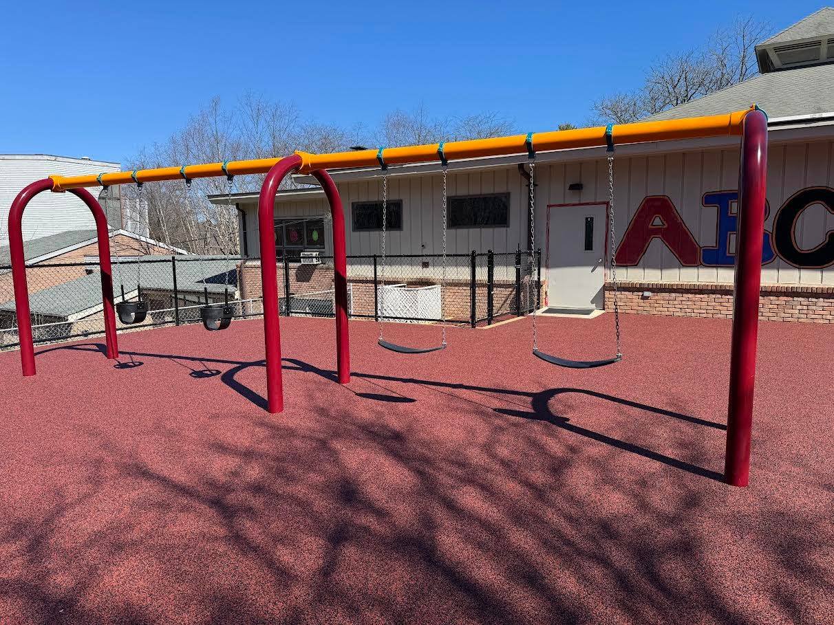 Empty swing set on a playground with a building in the background