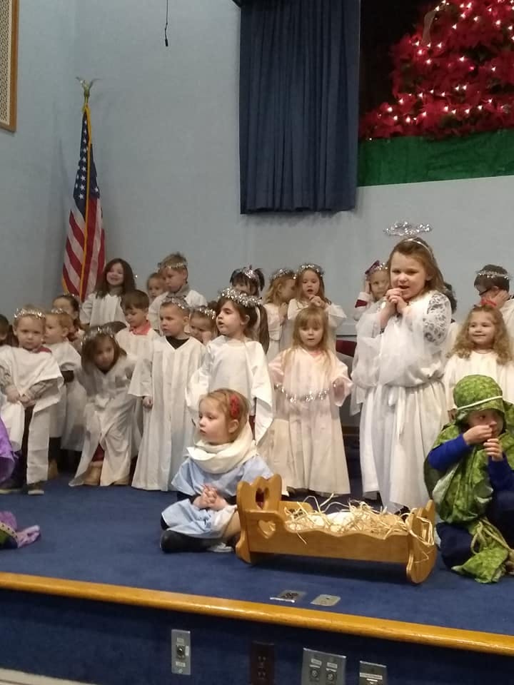 Children in costumes on a stage with a manger