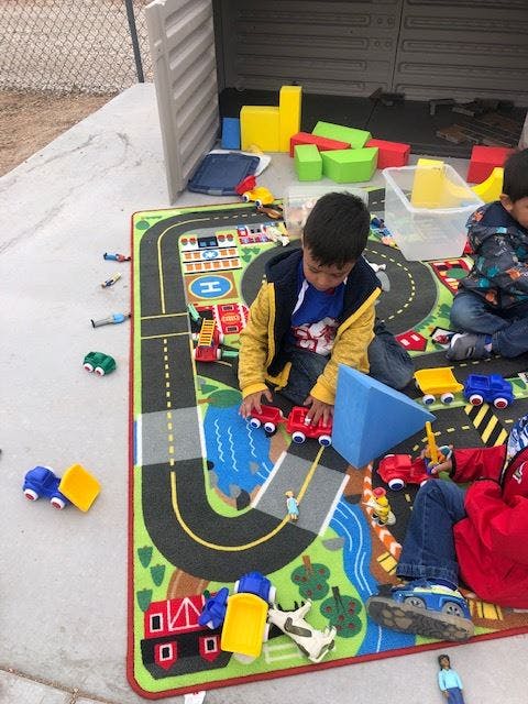 Child playing with toy cars on a road map rug