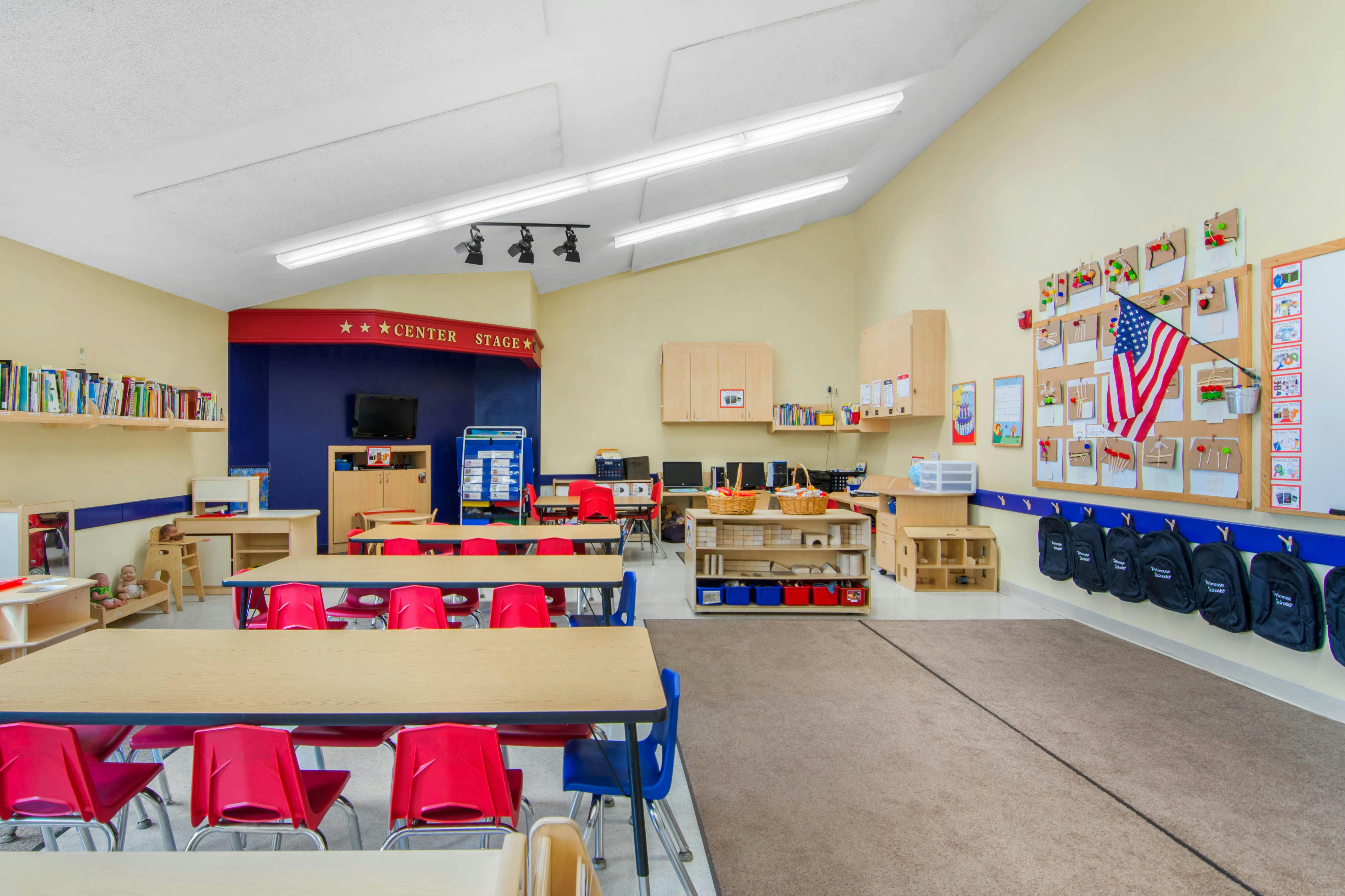 Classroom with tables, red and blue chairs, and a 'Center Stage' area