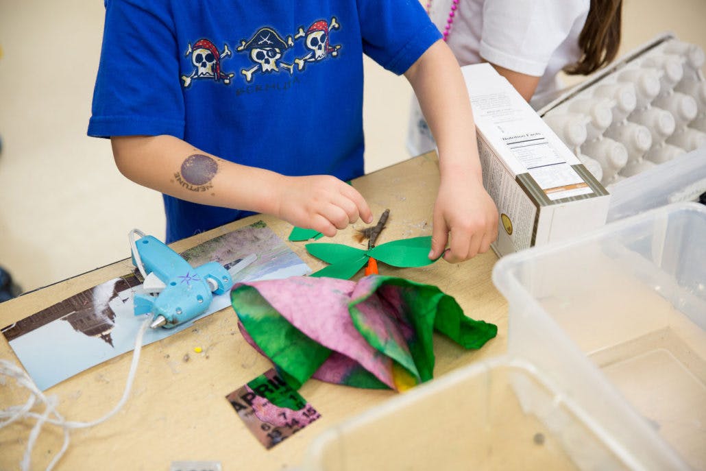 Child making crafts with paper and glue gun