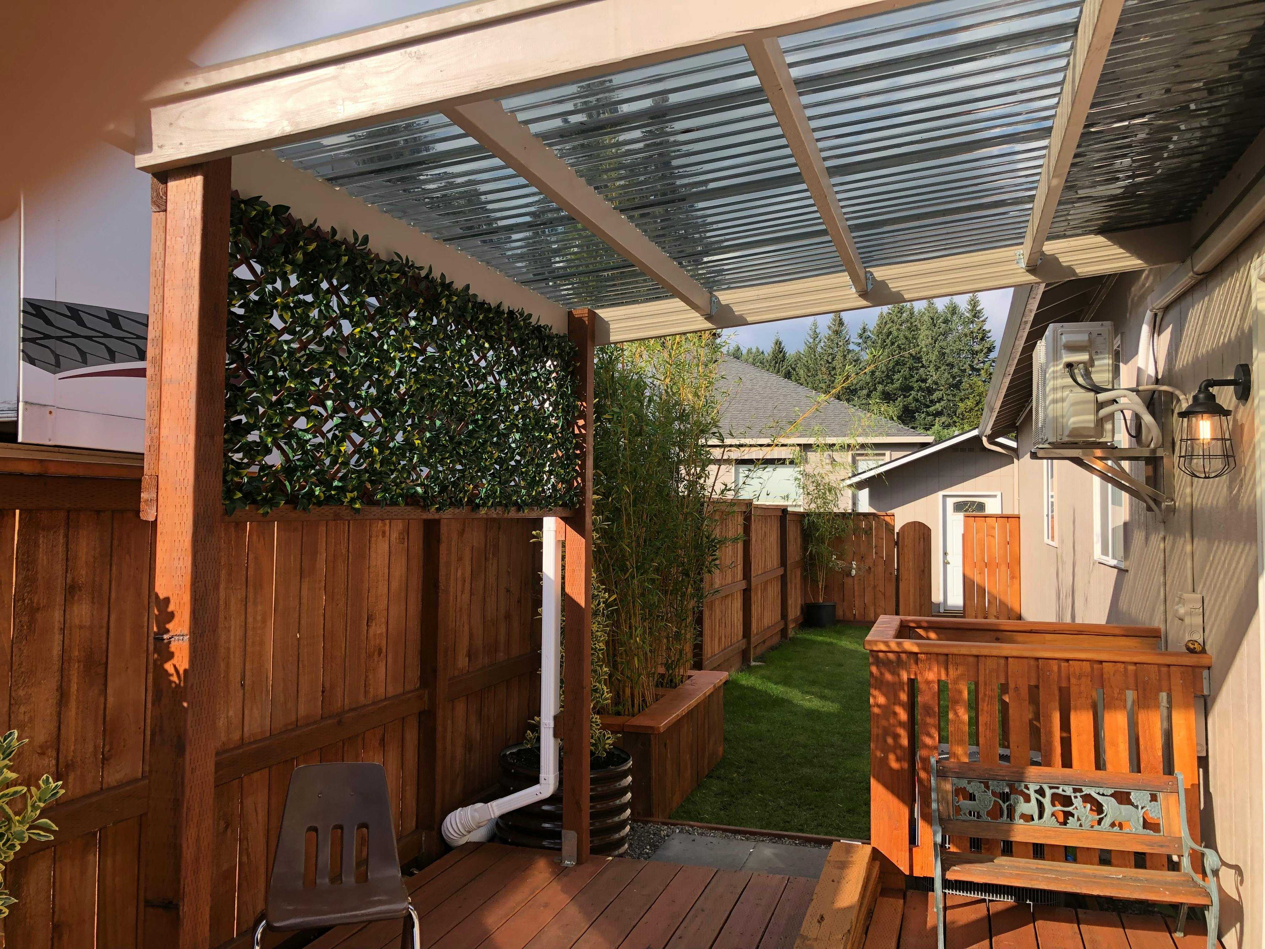 Outdoor patio with a clear corrugated roof and wooden fence