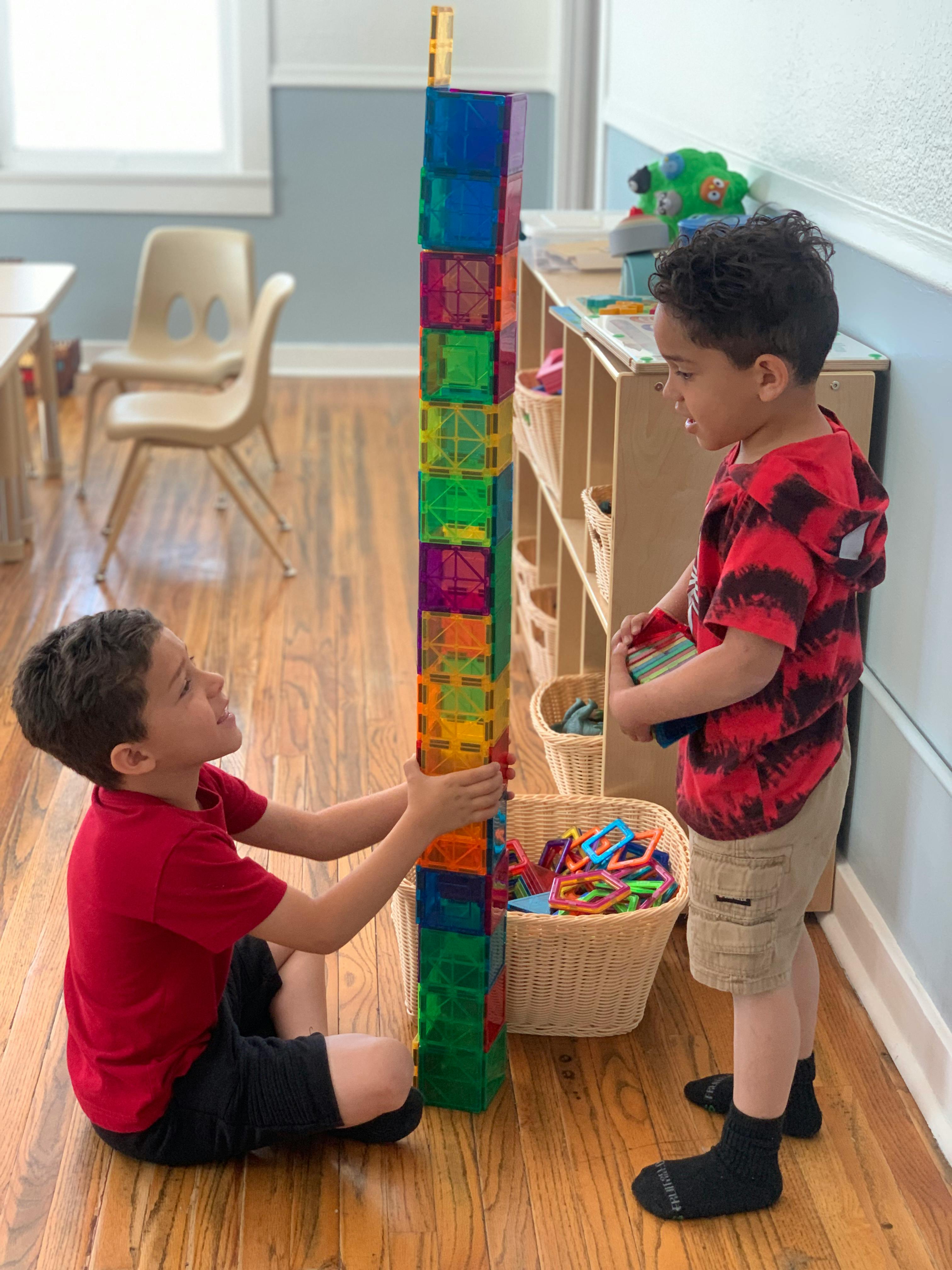 Two children building a tall tower with colorful blocks