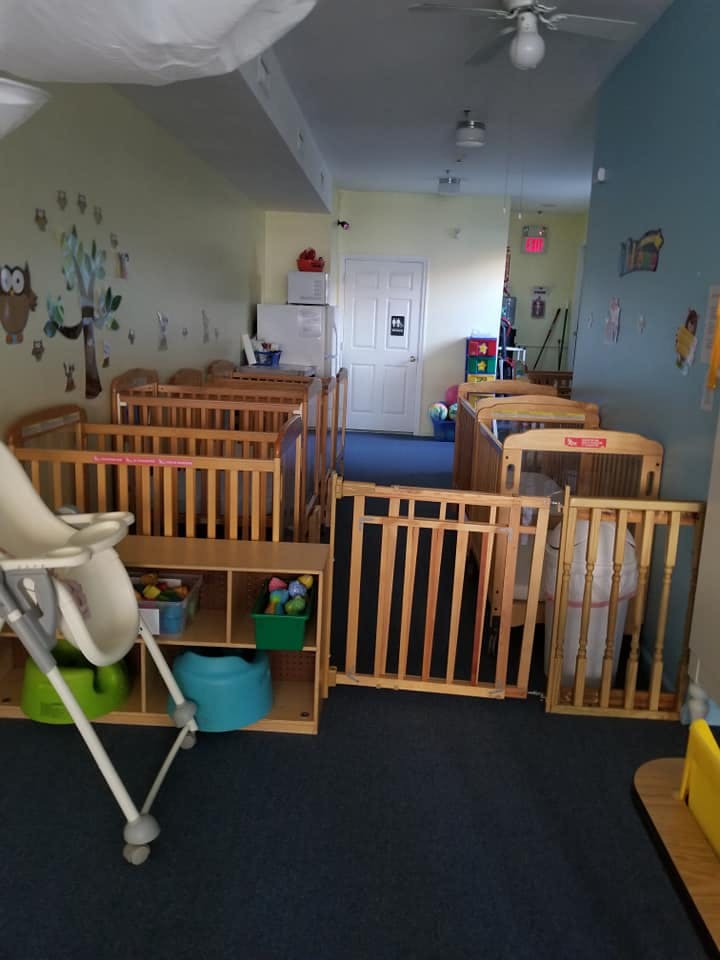 Nursery room with multiple cribs and a high chair