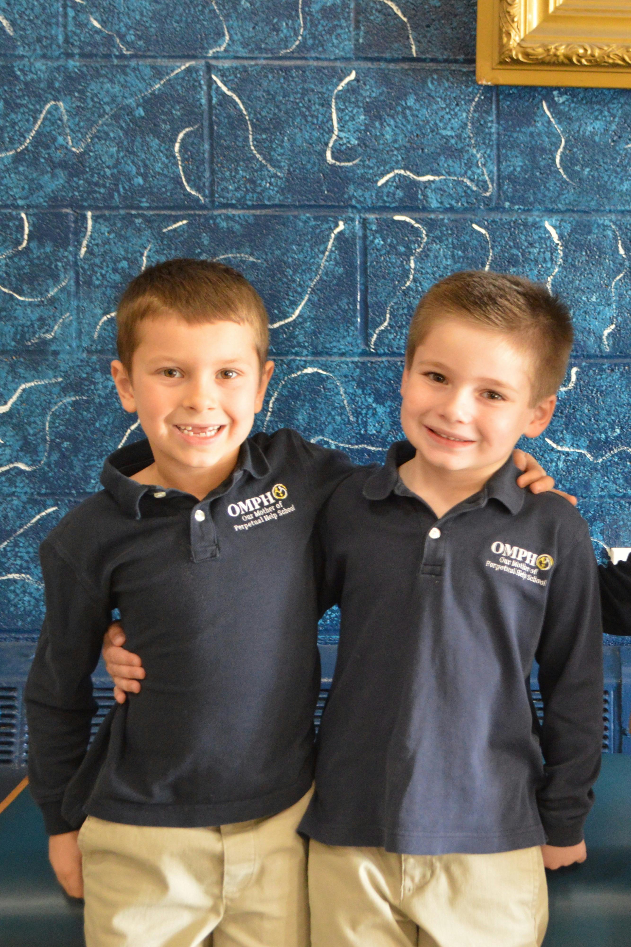 Two children in matching shirts standing with arms around each other