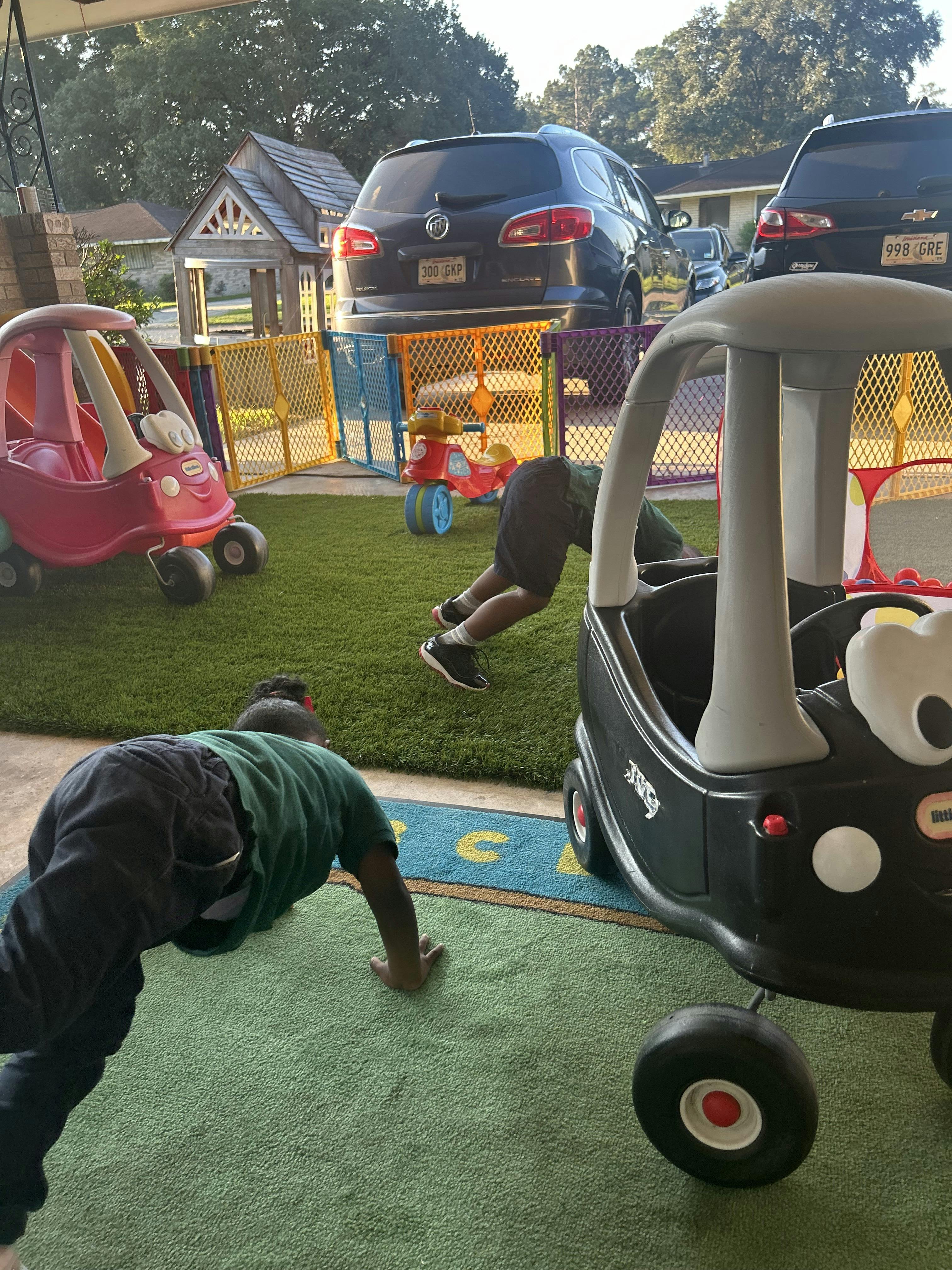 Two children playing on a green rug with toy cars