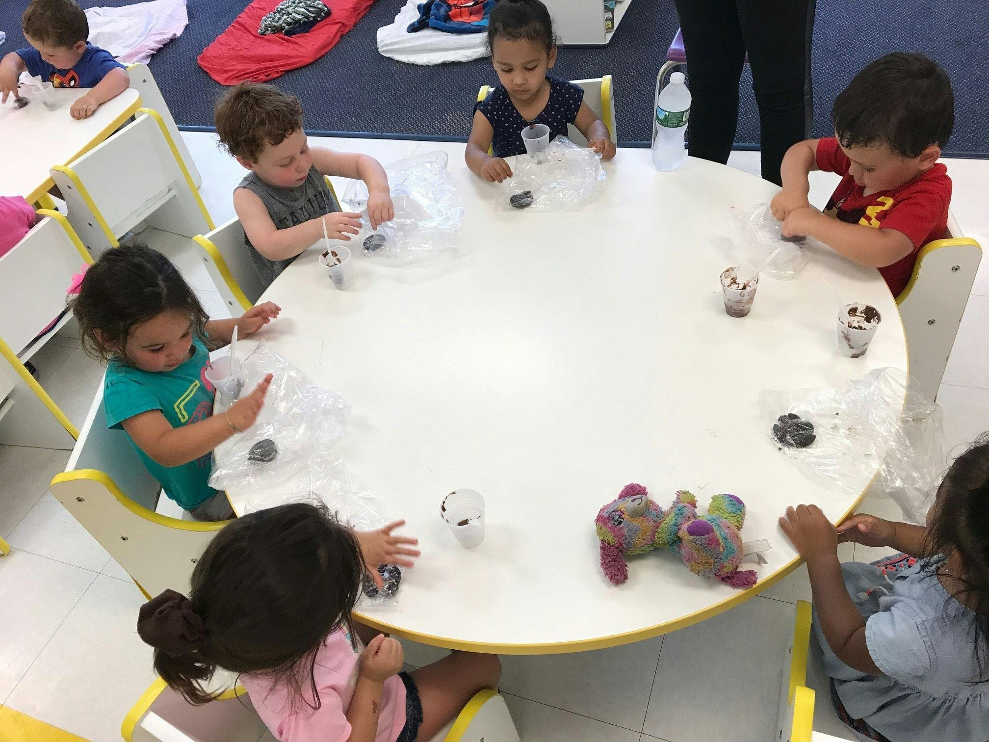 Children sitting around a table with cups and objects