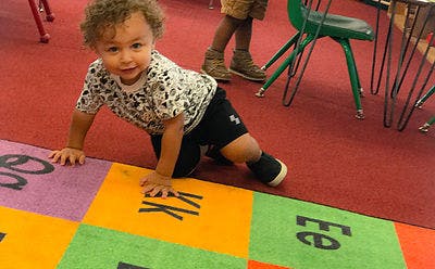 Child crawling on a colorful alphabet mat