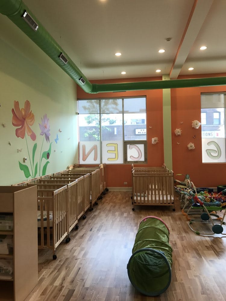 Nursery room with multiple cribs and a green play tunnel