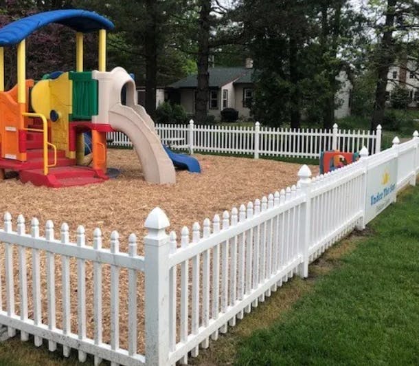 Playground with colorful slide and white picket fence