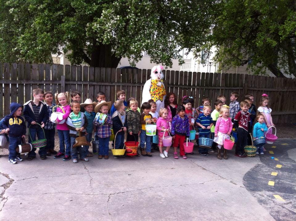 Children holding baskets with a person in a bunny costume