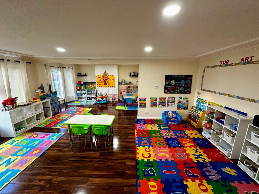 Playroom with colorful alphabet mats, small tables, and shelves with shelves of toys