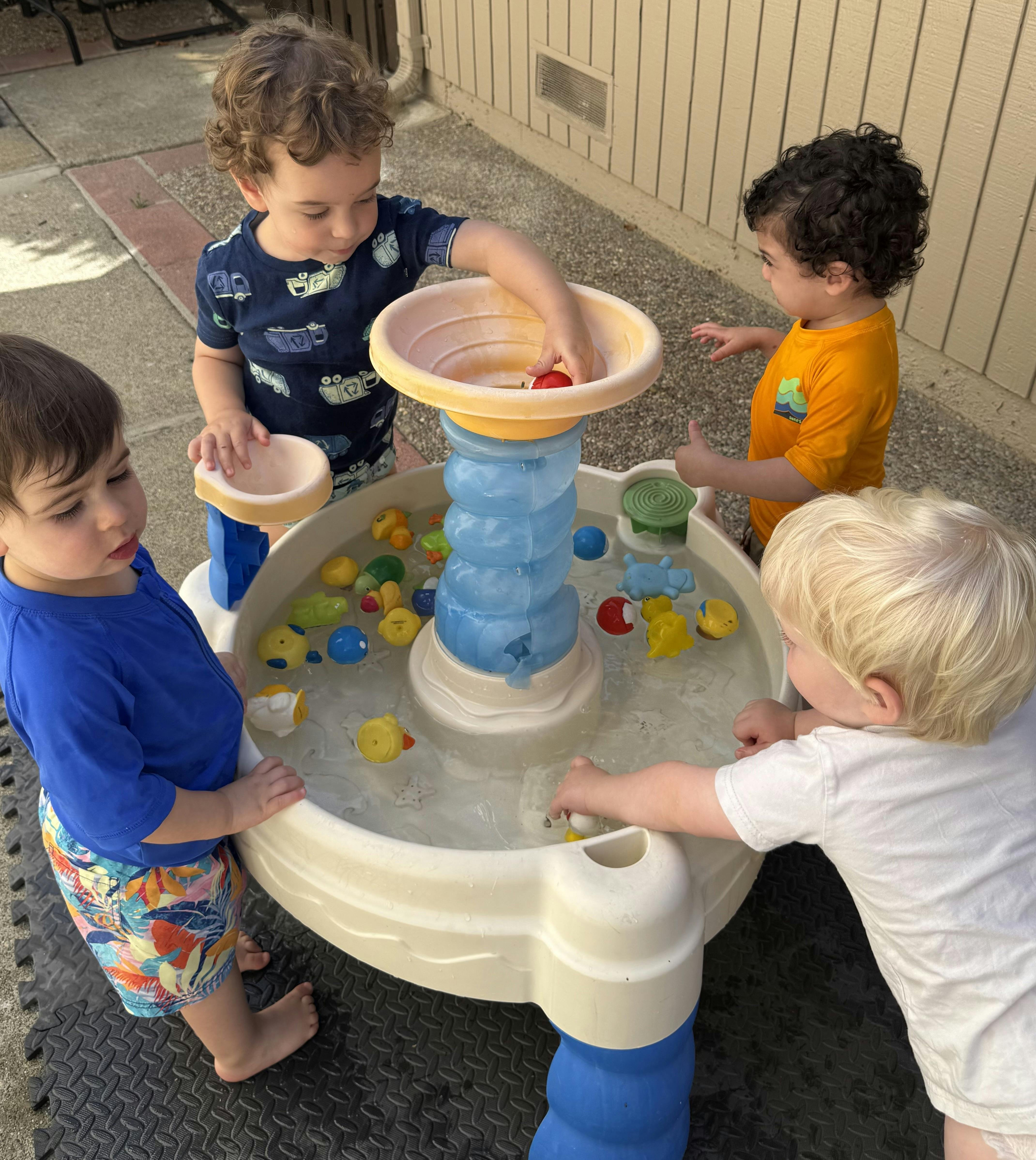 Four children playing with a water table outdoors