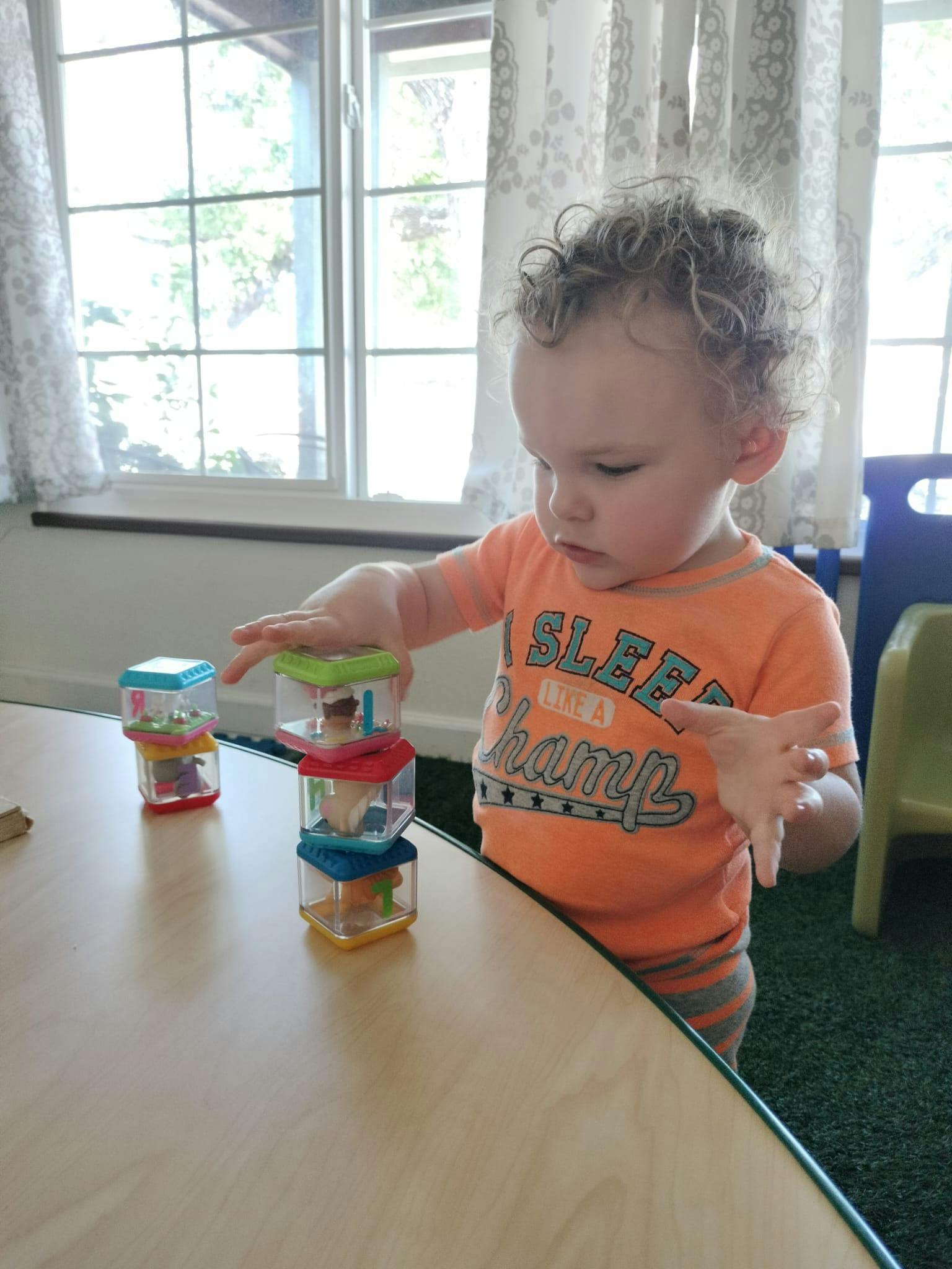 Child stacking colorful clear blocks on a table