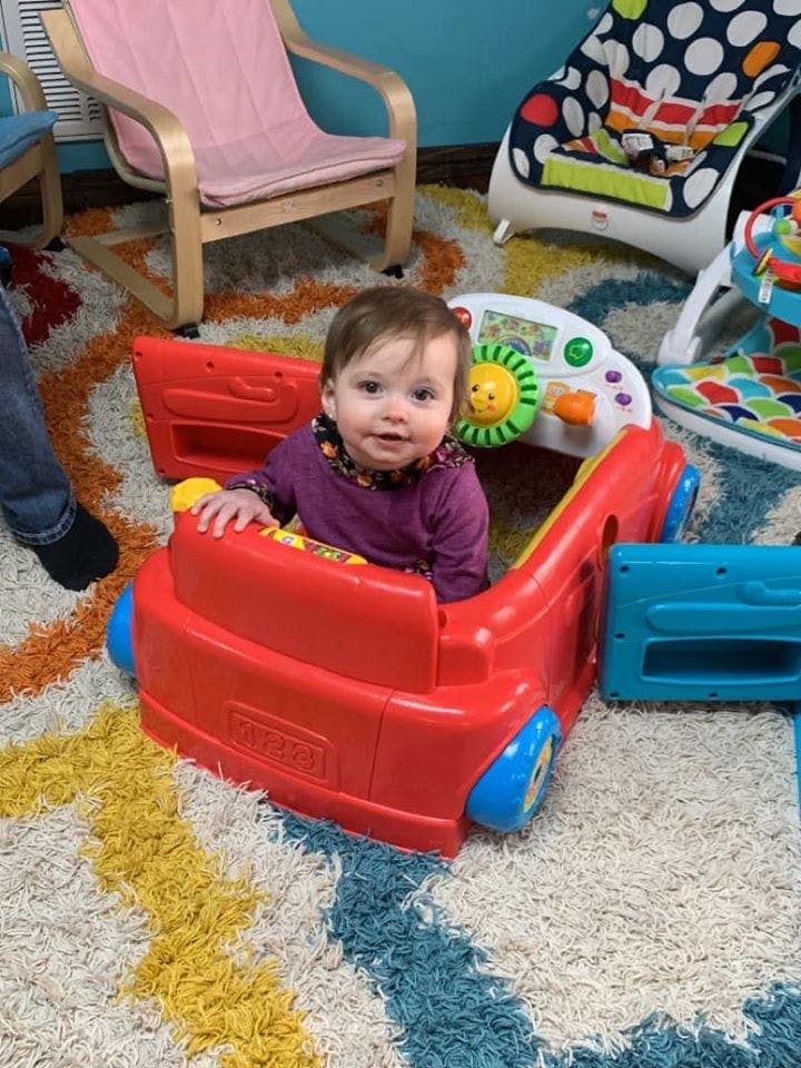 Child sitting in a red toy car